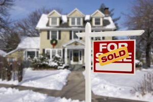 home in the winter marked for sale with a sold sign over it