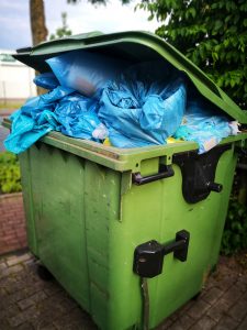 green garbage can filled with junk