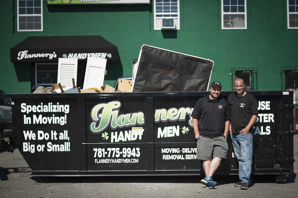 Todd and Rory Flannery standing in front of their dumpster for junk removal