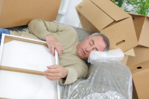 mover stressed and laying down with boxes around him