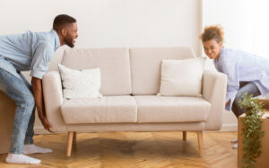 man and woman struggling to lift a couch on their own