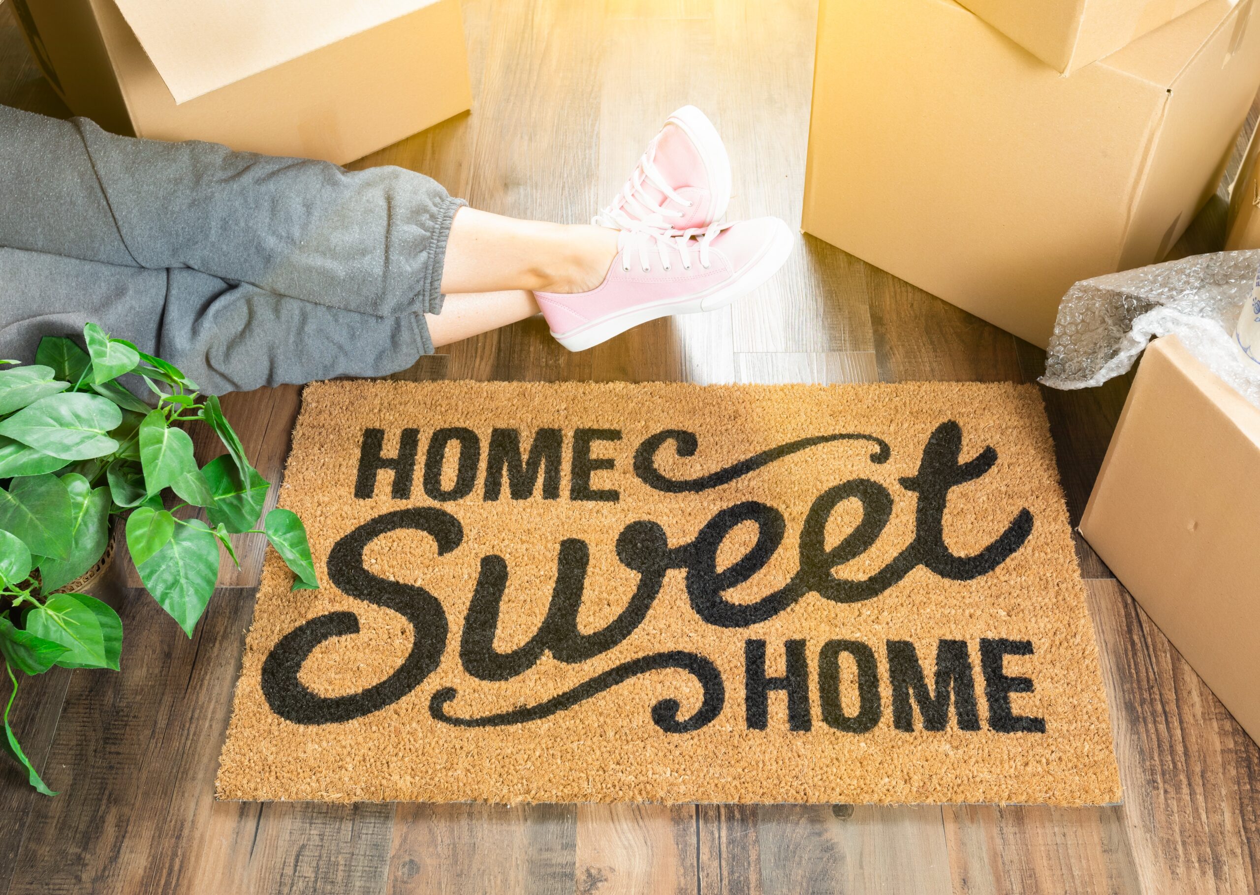 home sweet home welcome mat as woman lays down around her packaged boxes
